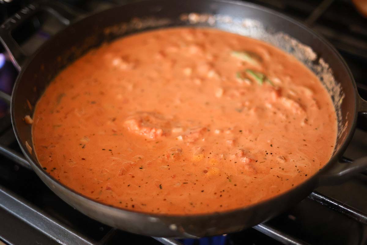 vodka sauce cooking in a black skillet on the stove. 
