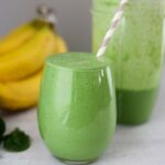glass filled with green spinach banana smoothie.