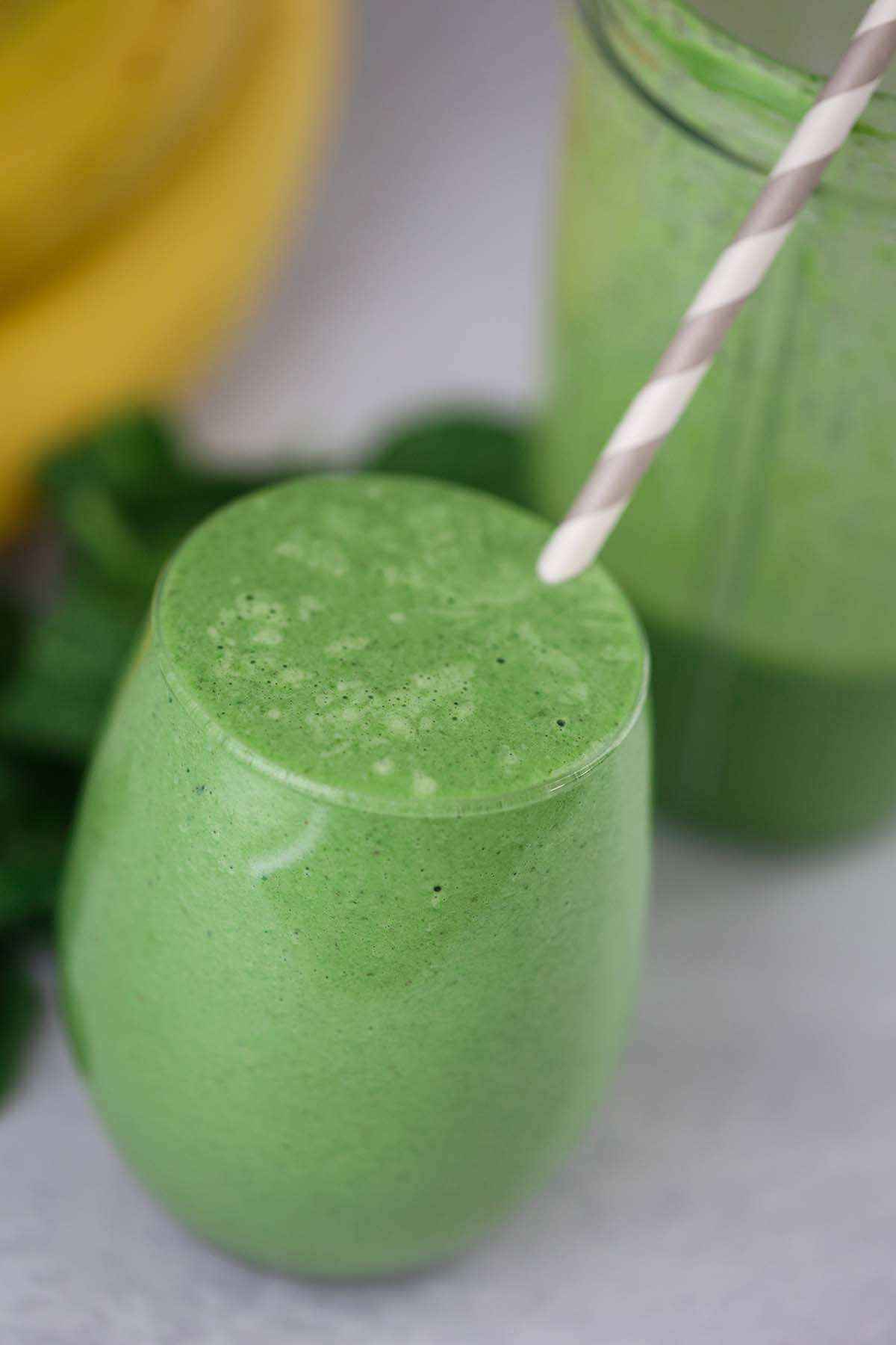 spinach banana smoothie with a straw.