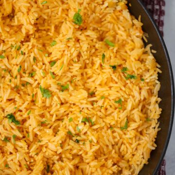 Yellow rice in a black skillet up close.