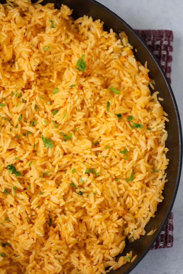 Yellow rice in a black skillet up close.