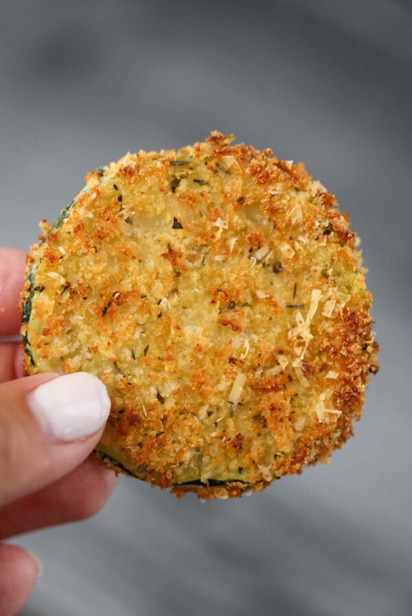 hand holding an air fryer zucchini chip up close.