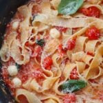 cherry tomato pasta with basil and cheese on top.
