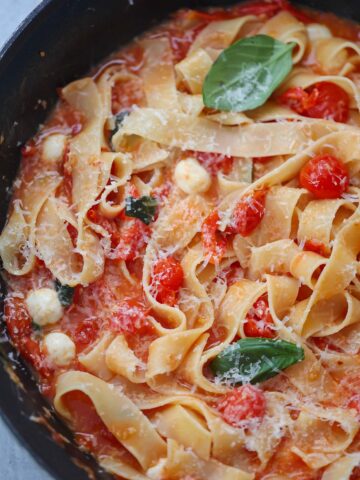 cherry tomato pasta with basil and cheese on top.