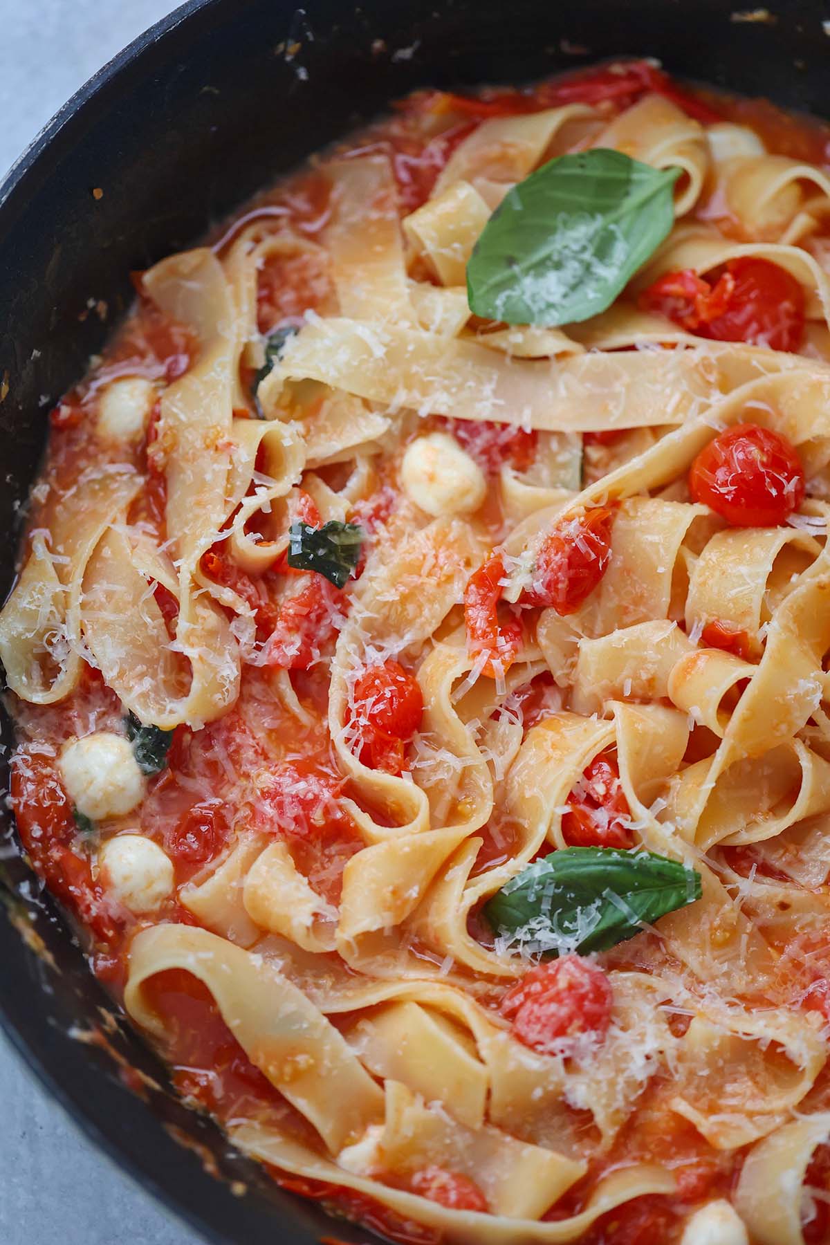 cherry tomato pasta with basil and cheese on top. 