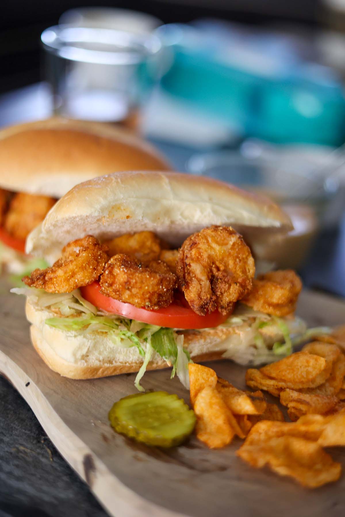 crispy shrimp po'boy sandwich with chips and a pickle. 
