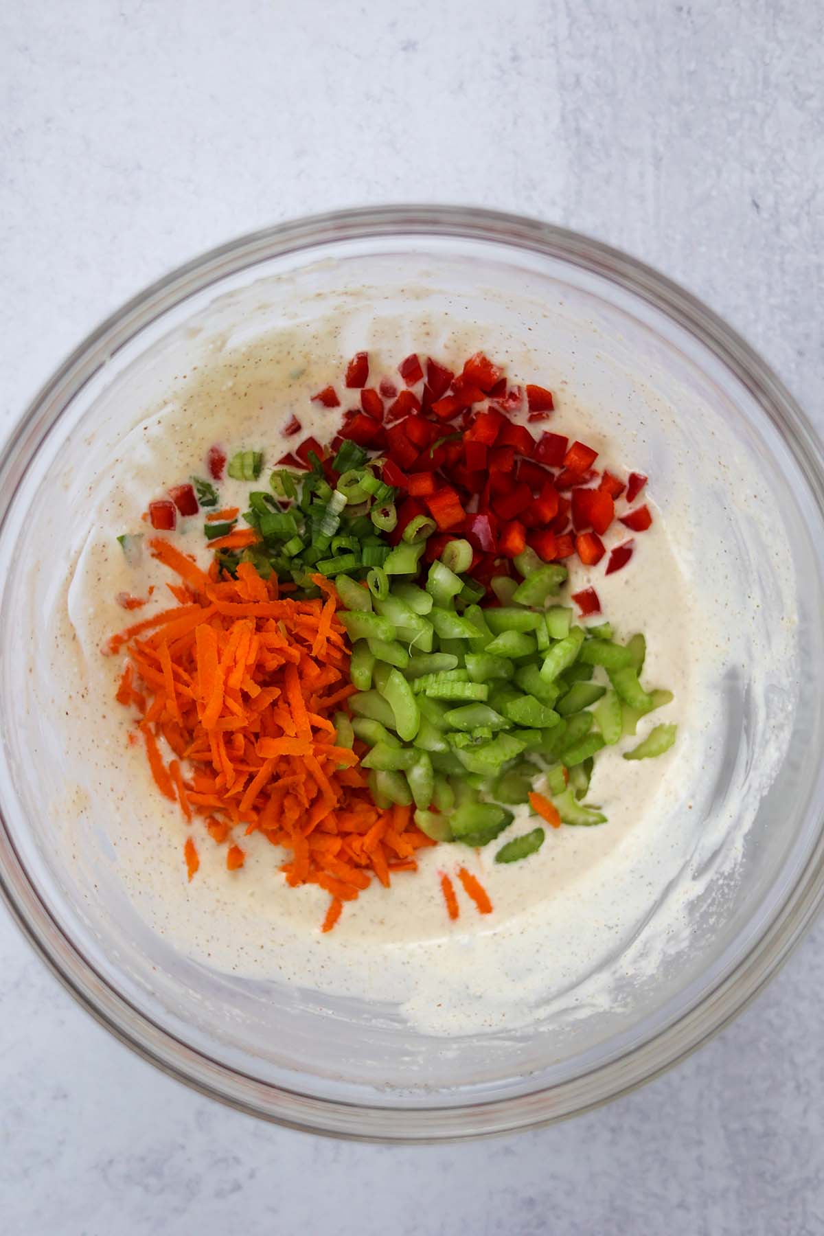 carrots, celery, red peppers, scallions, and dressing in a bowl. 