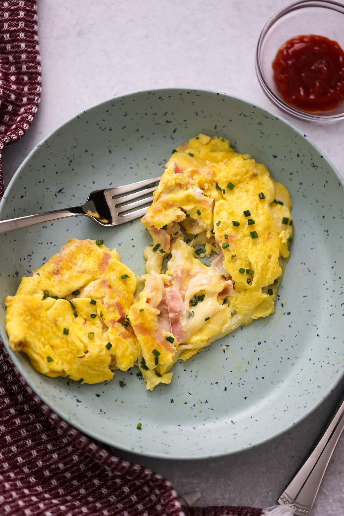 An omelet sliced in half with melted cheese and ham. 