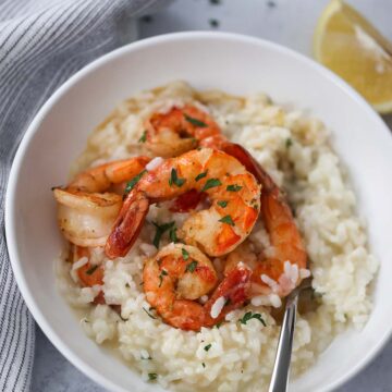 shrimp risotto in a white bowl with a fork.