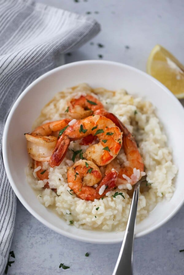 shrimp risotto in a white bowl with a fork.