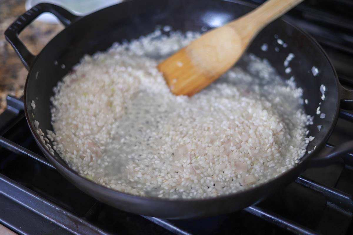 arborio rice and chicken stock cooking in a skillet. 