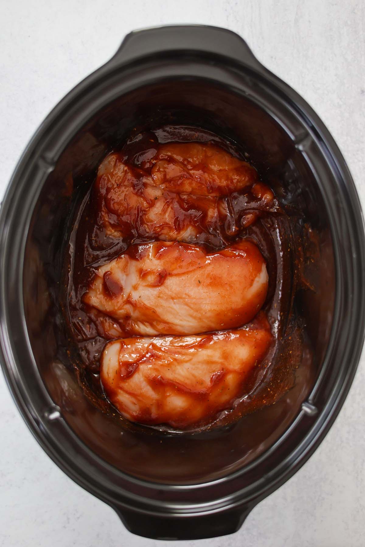 three chicken breasts and barbecue sauce in the slow cooker. 