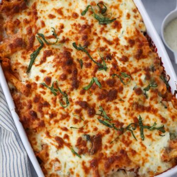 baked ziti in a 9x13 baking dish with cheese and red pepper flakes on the side.