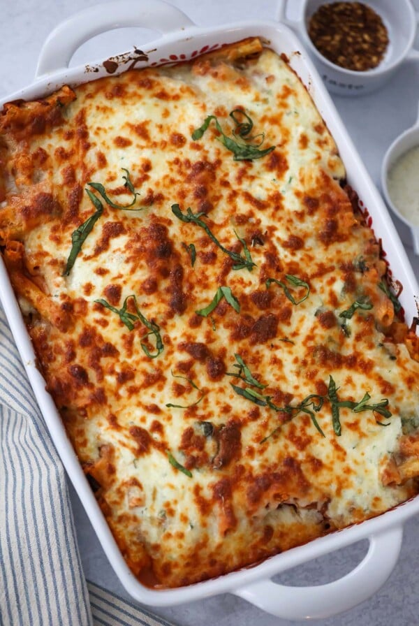 baked ziti in a 9x13 baking dish with cheese and red pepper flakes on the side.