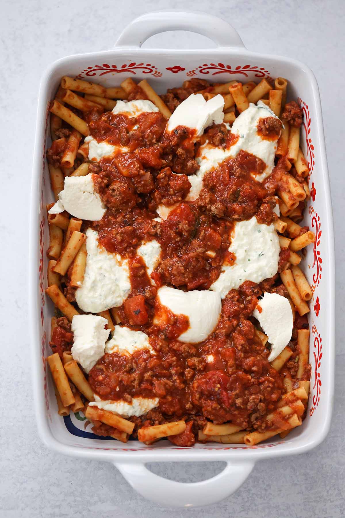 layered pasta, meat sauce, ricotta cheese, and fresh mozzarella in a baking dish. 