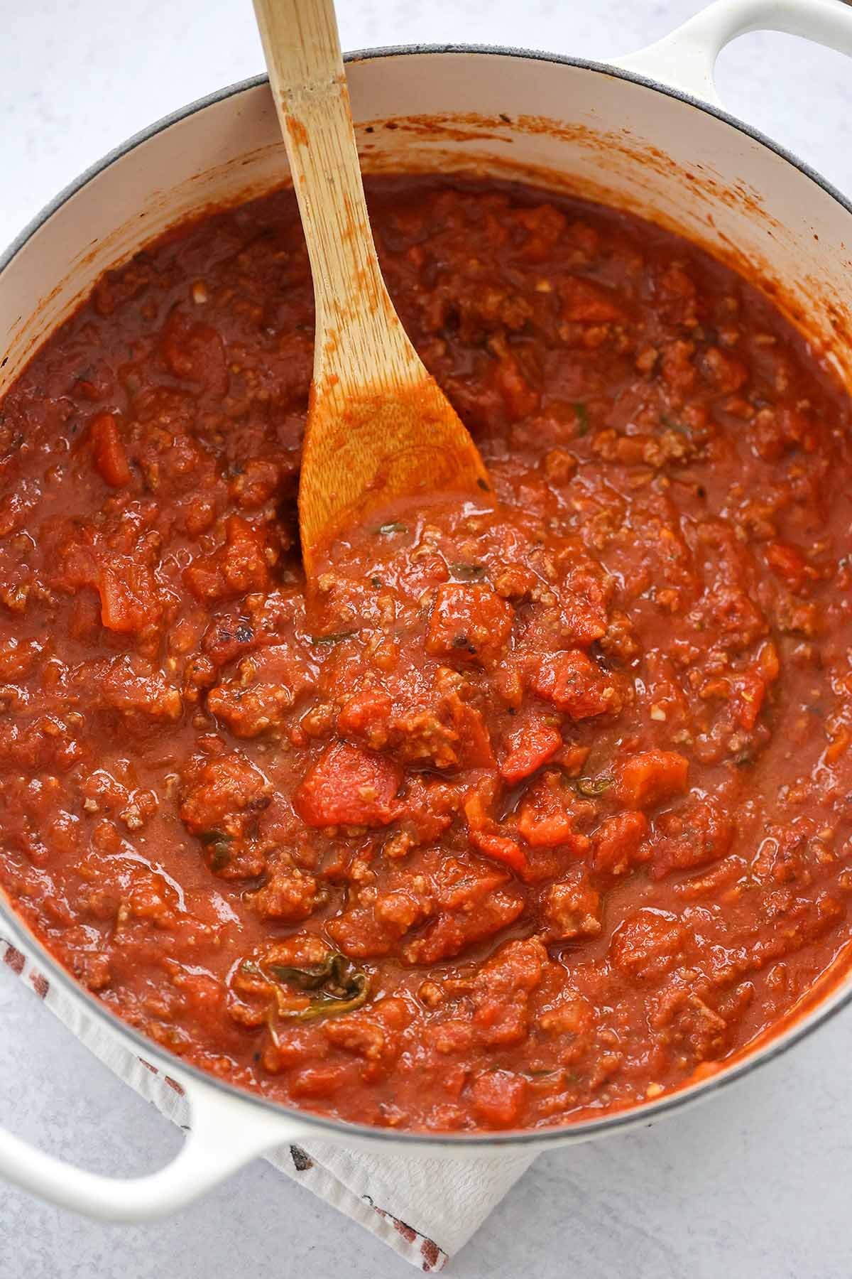meat sauce in a large pot with a wooden spoon. 