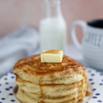 four buttermilk pancakes with butter and syrup on top.