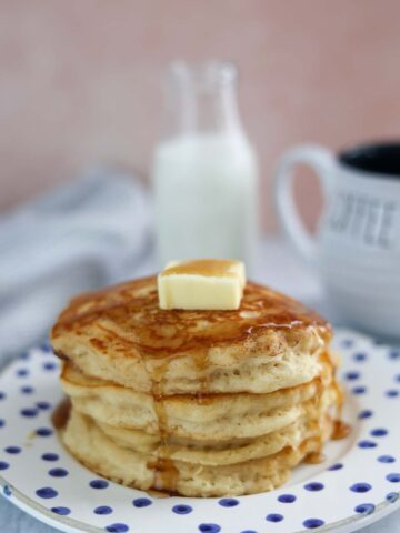 four buttermilk pancakes with butter and syrup on top.