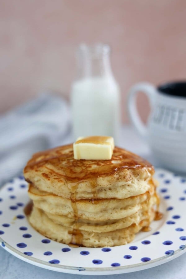 four buttermilk pancakes with butter and syrup on top.