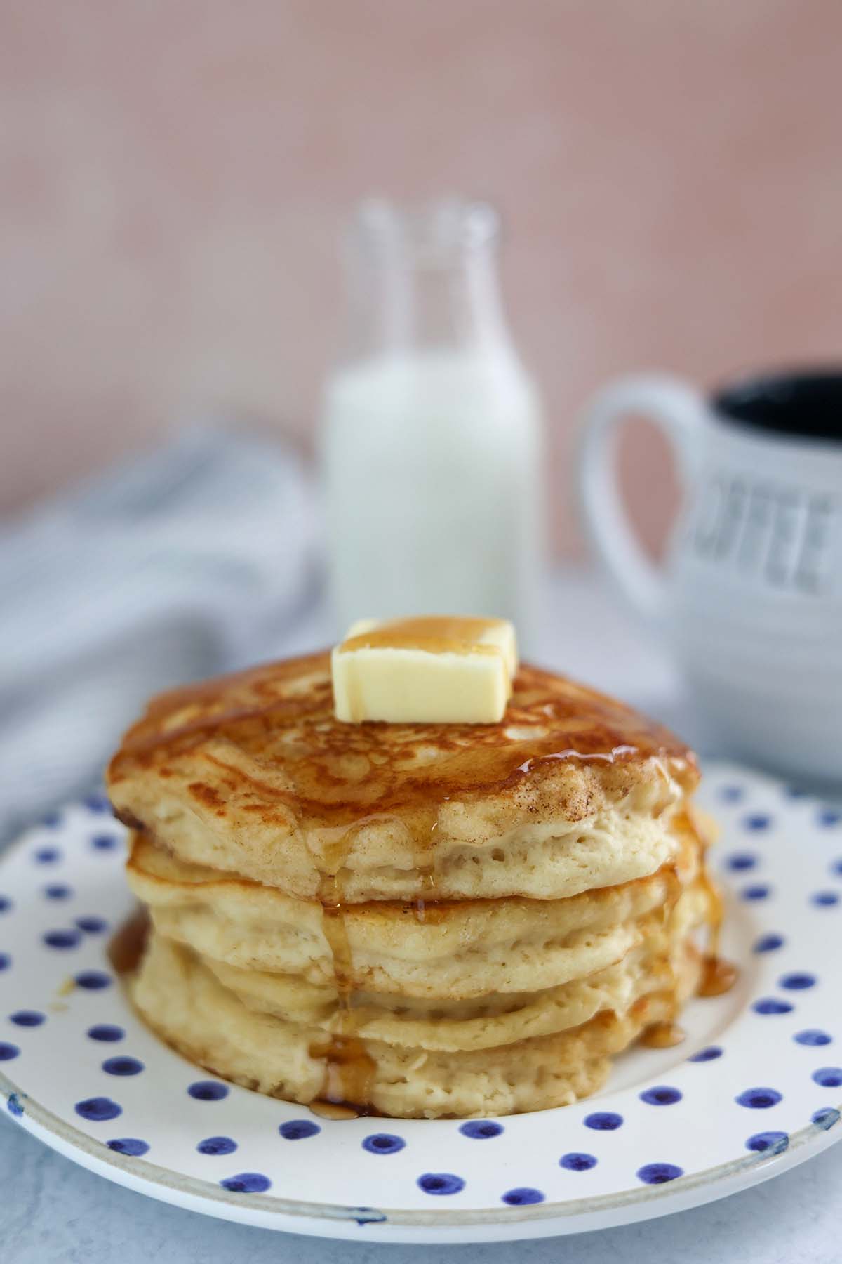 four buttermilk pancakes with butter and syrup on top. 