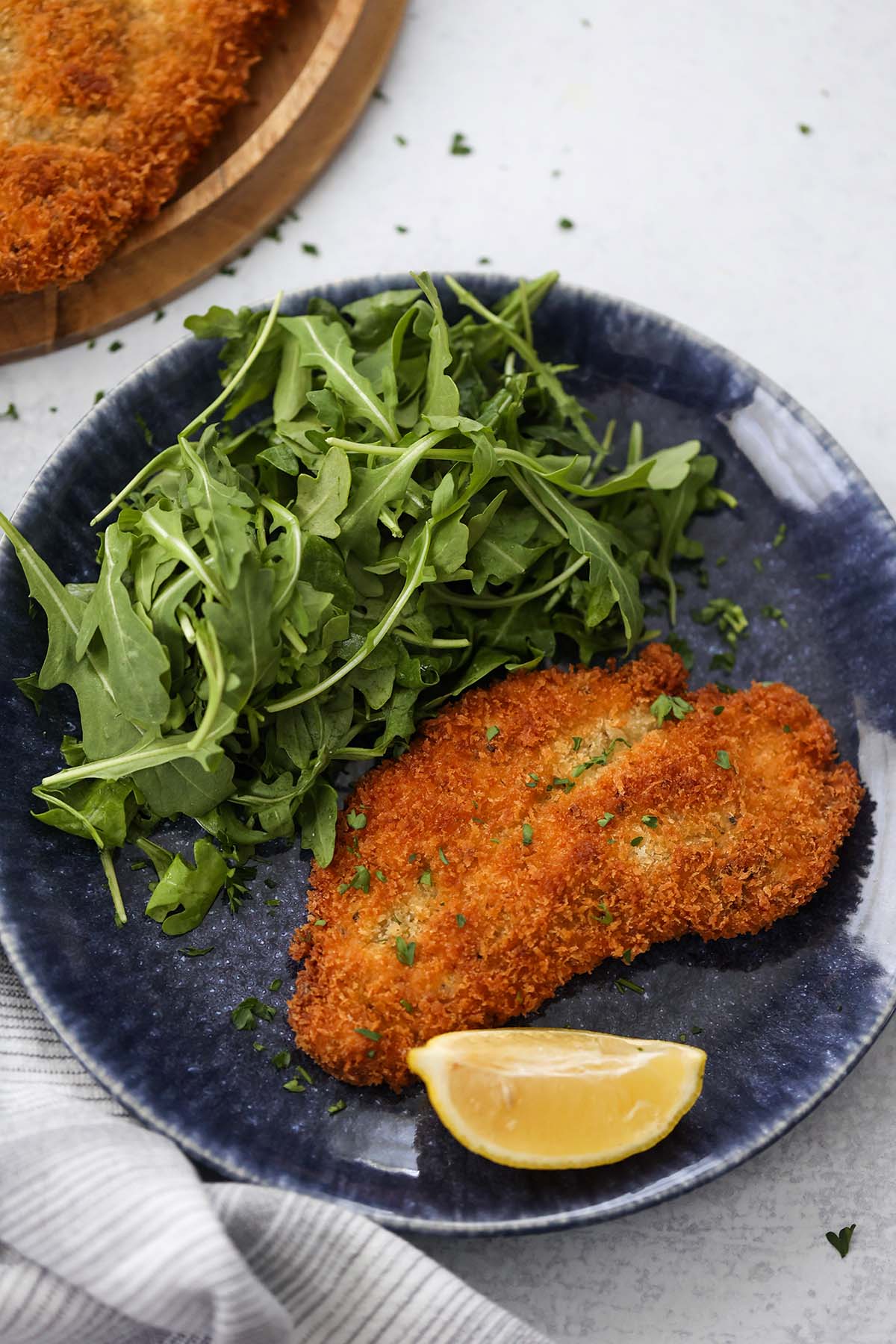 chicken milanese with a lemon wedge and arugula on the side. 