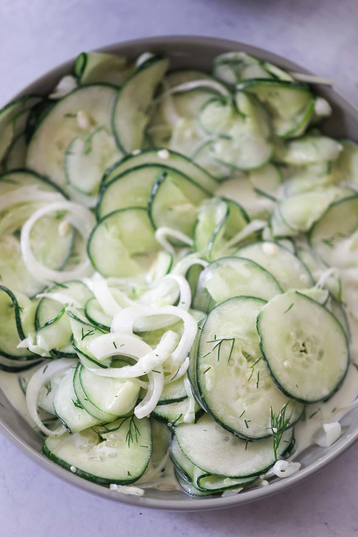 creamy cucumber salad with onions and dill on top. 