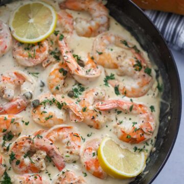 creamy shrimp piccata in a skillet with bread on the side.