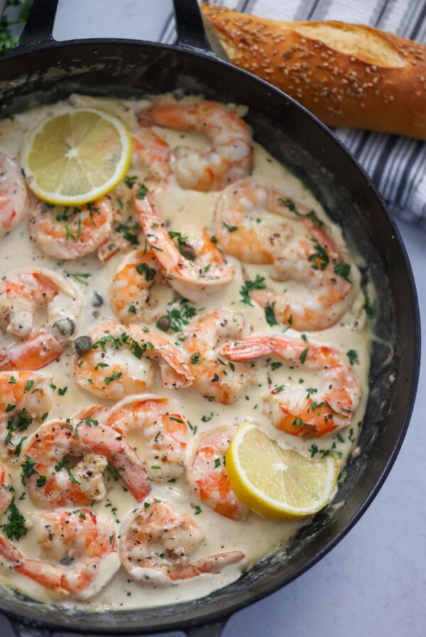 creamy shrimp piccata in a skillet with bread on the side.