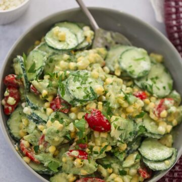 cucumber avocado tomato salad in a bowl with a spoon.