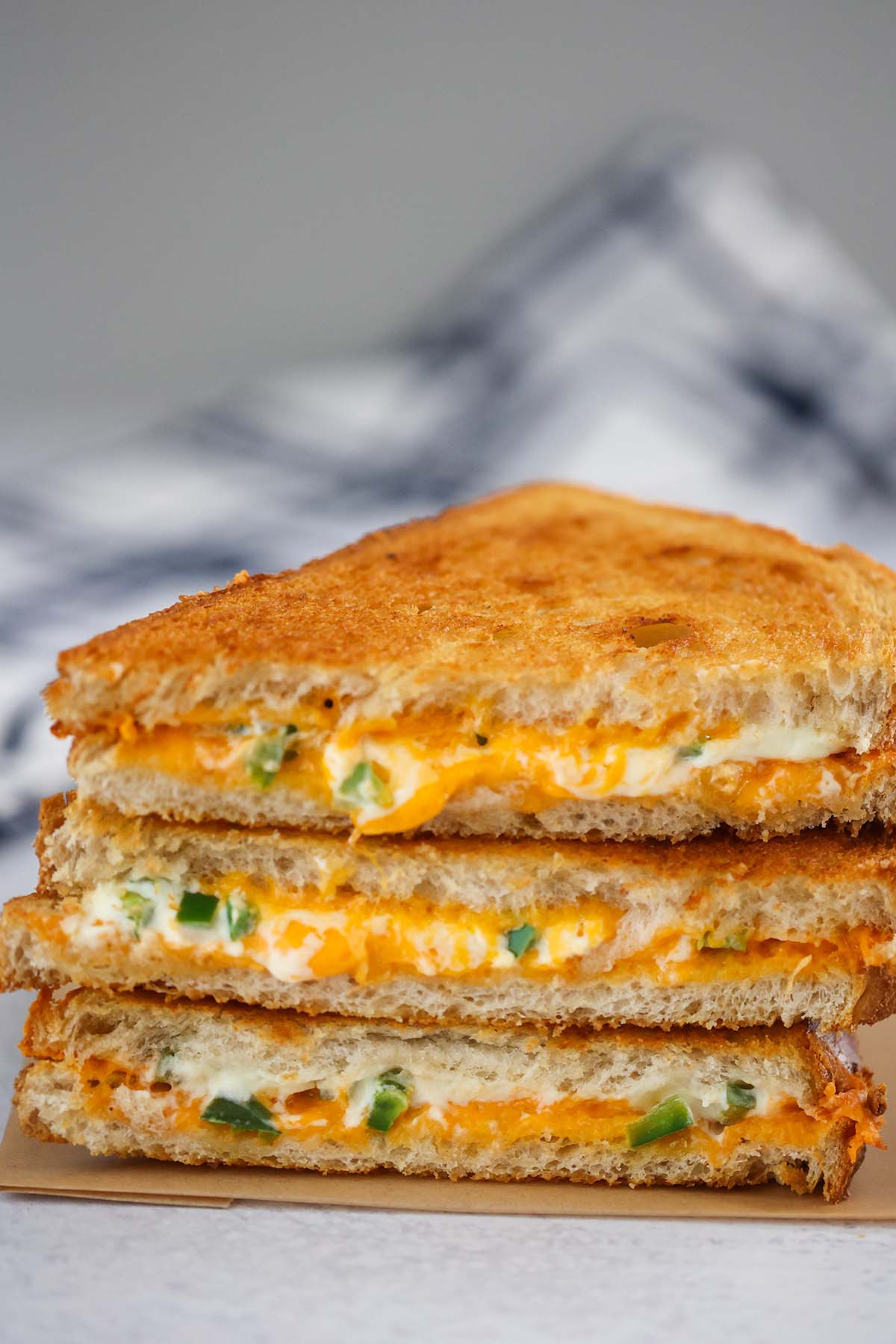 three jalapeno popper grilled cheese sandwiches stacked. 