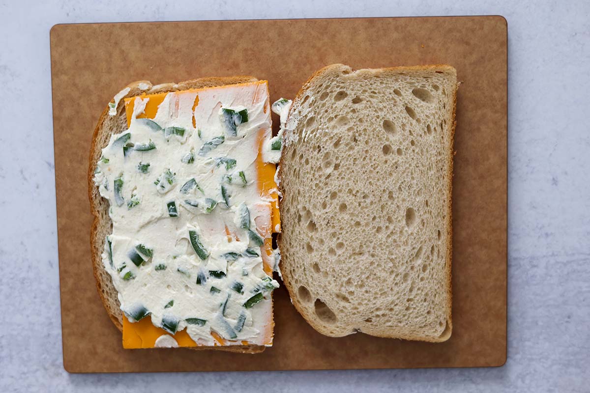 two bread slices with jalapeno cream cheese spread and cheddar cheese slices. 