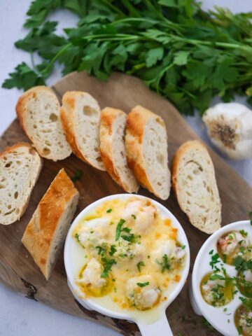 lobster cargot on a wooden board with bread and parsley on the side.