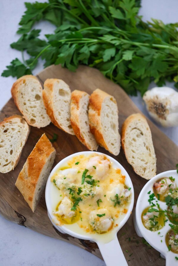 lobster cargot on a wooden board with bread and parsley on the side.