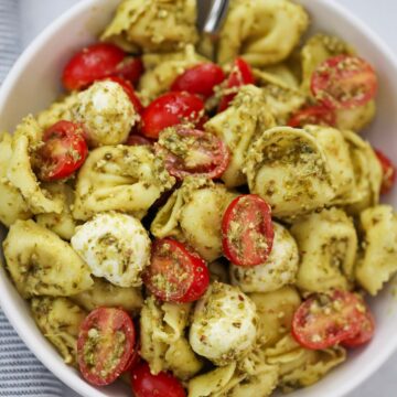 pesto tortellini salad in a bowl with a spoon.