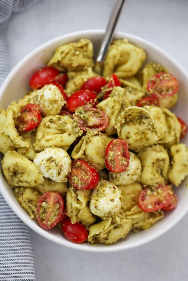 pesto tortellini salad in a bowl with a spoon.