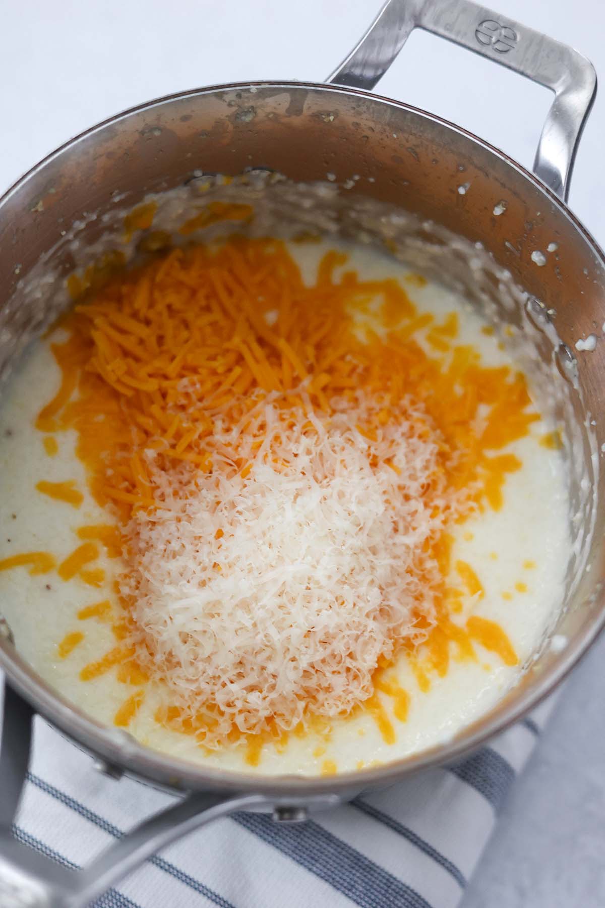 cooked grits with cheddar cheese and parmesan cheese in a saucepan. 