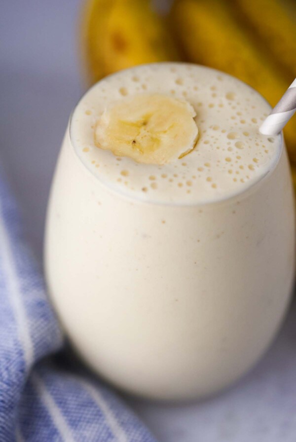 banana milkshake in a glass with a slice of banana on top and a straw.