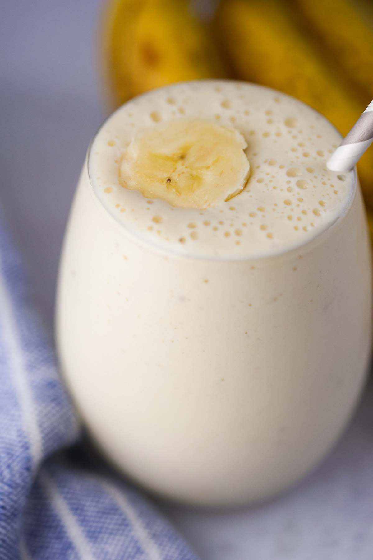 banana milkshake in a glass with a slice of banana on top and a straw. 