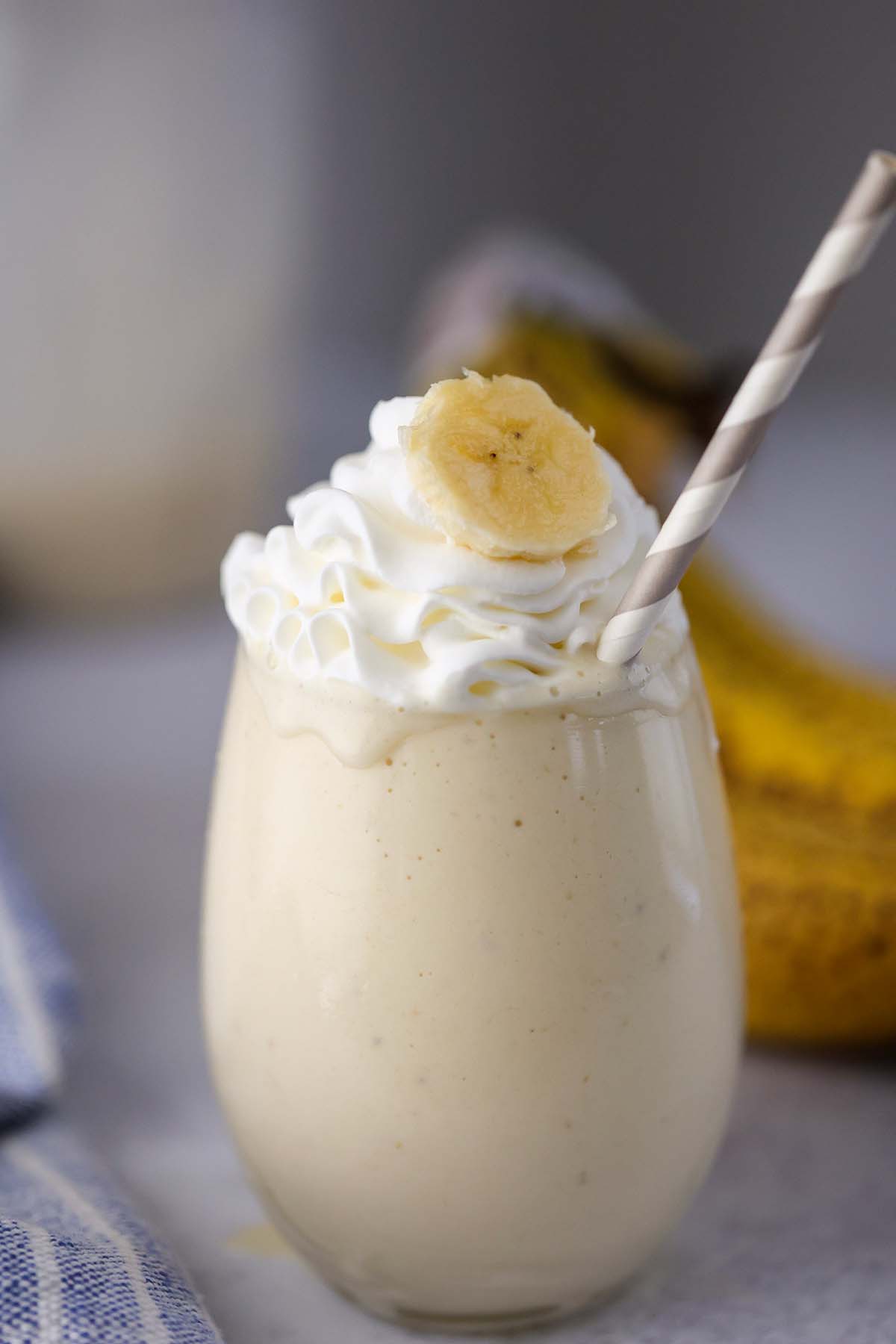 banana milkshake in a glass with whipped cream on top. 
