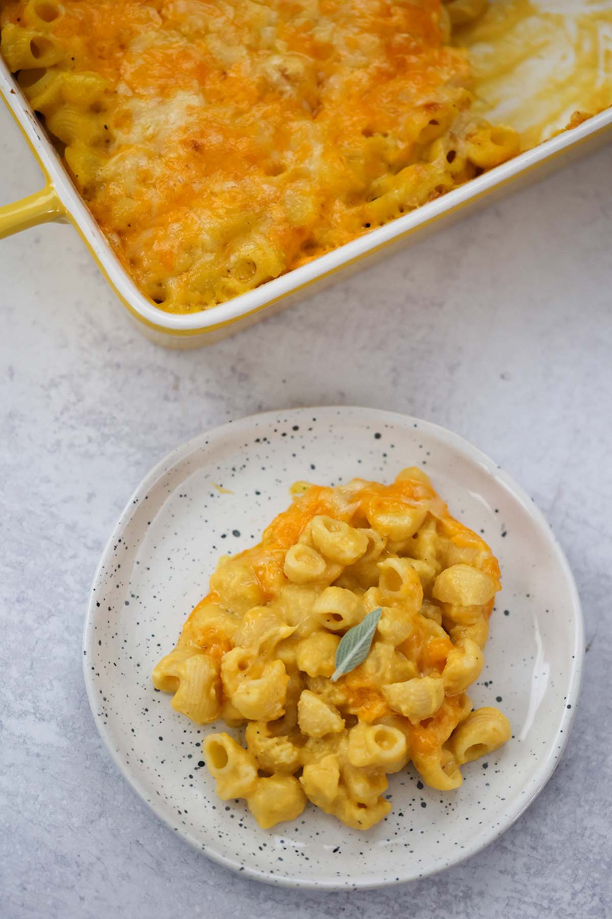 mac and cheese on a plate with sage on top. 
