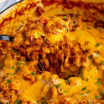 chili mac and cheese in a large pot with a spoon.