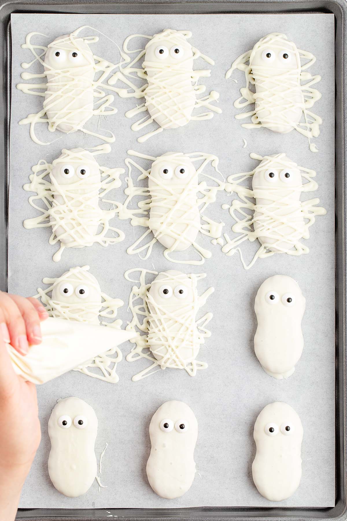 person decorating cookies with piping bag.