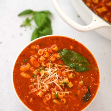 pasta fagioli soup in a bowl with a pot on the side.