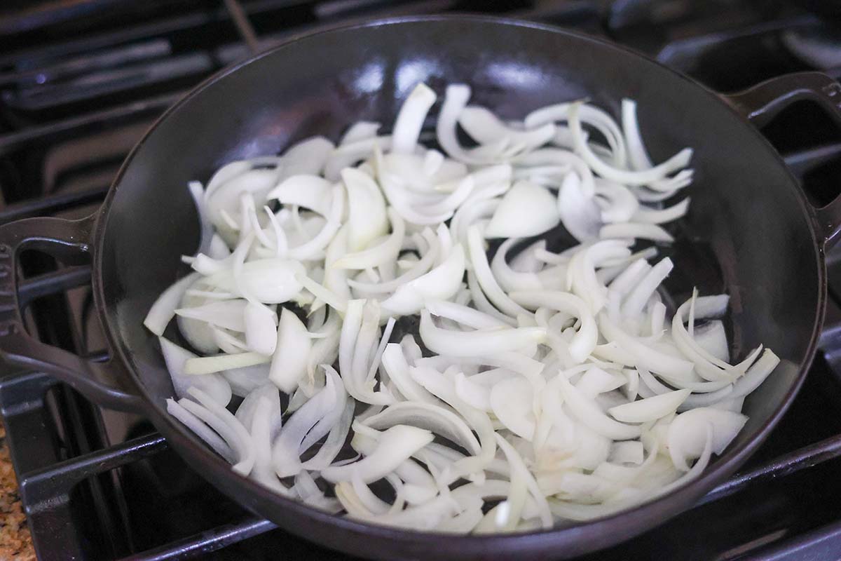 raw onion slices in a skillet on the stovetop. 