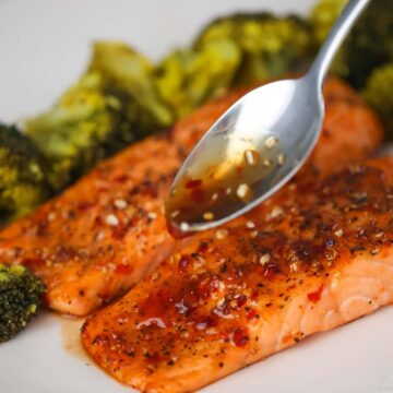 spoon drizzling honey glaze over cooked salmon.