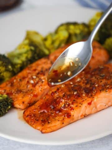 spoon drizzling honey glaze over cooked salmon.