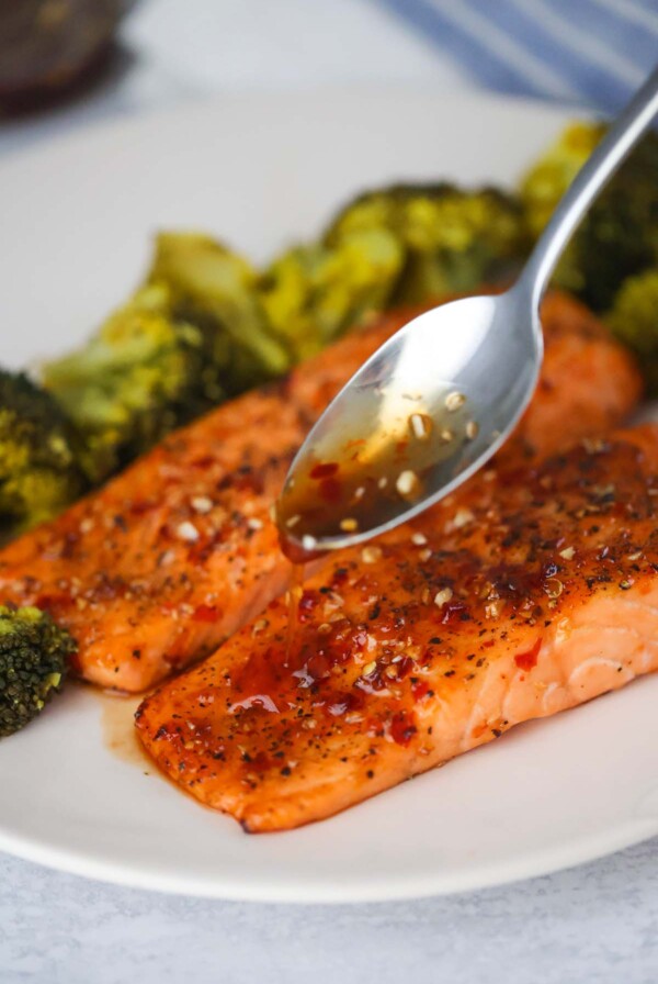 spoon drizzling honey glaze over cooked salmon.