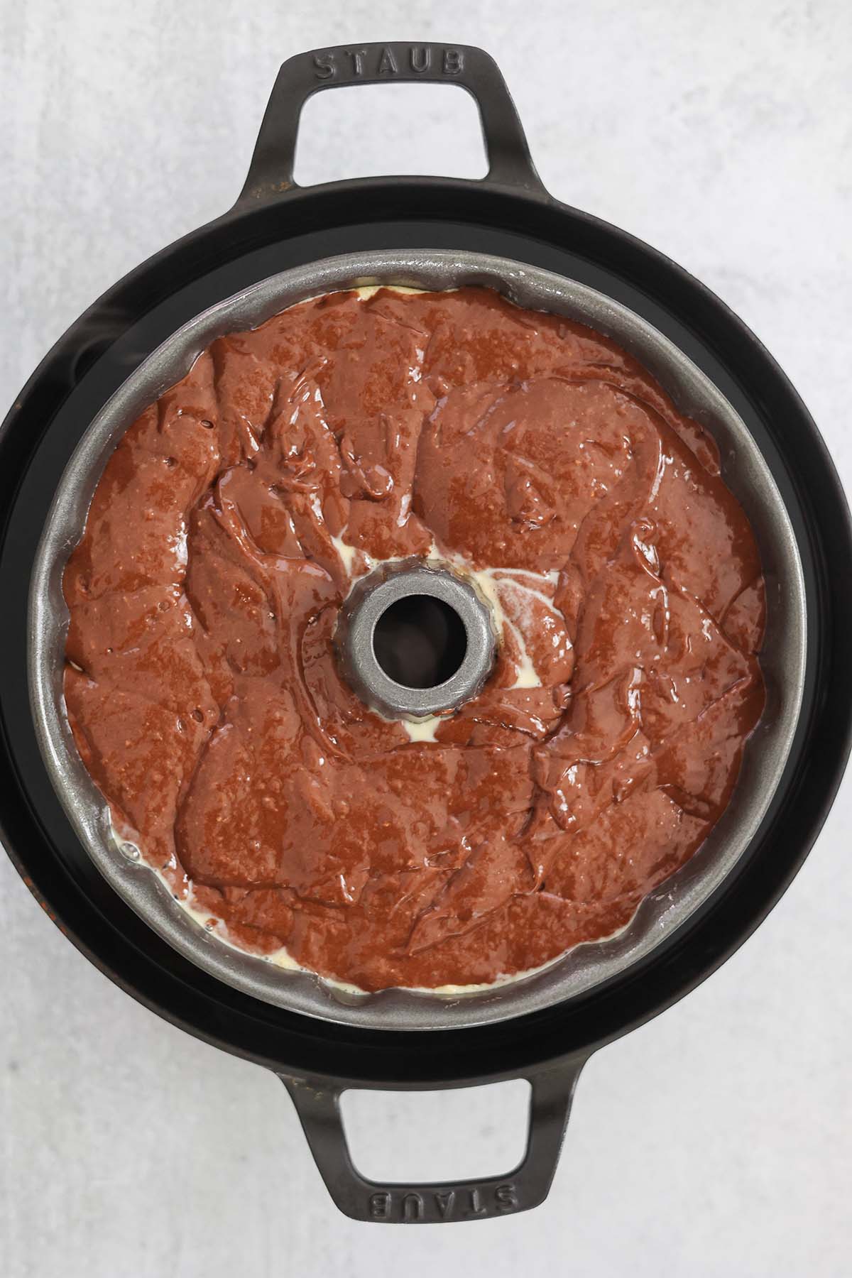 bundt pan in a bain-marie with chocolate cake batter on top of flan mixture. 
