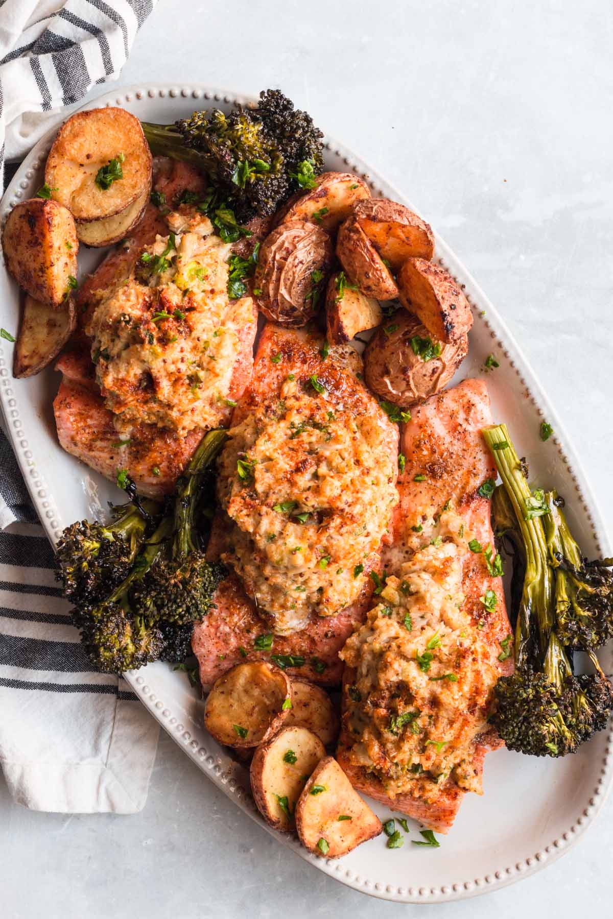 crab stuffed salmon on a platter with broccoli and potatoes. 