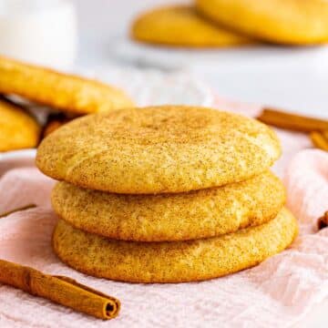 three snickerdoodle cookies with cinnamon sticks on the side.